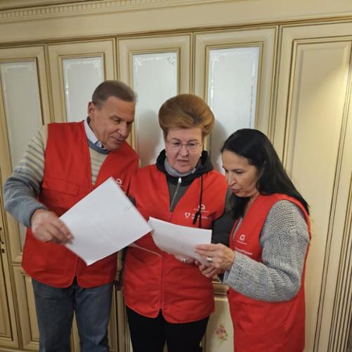 Grupa osób w kamizelkach z logo Polska pomoc przegląda dokumenty