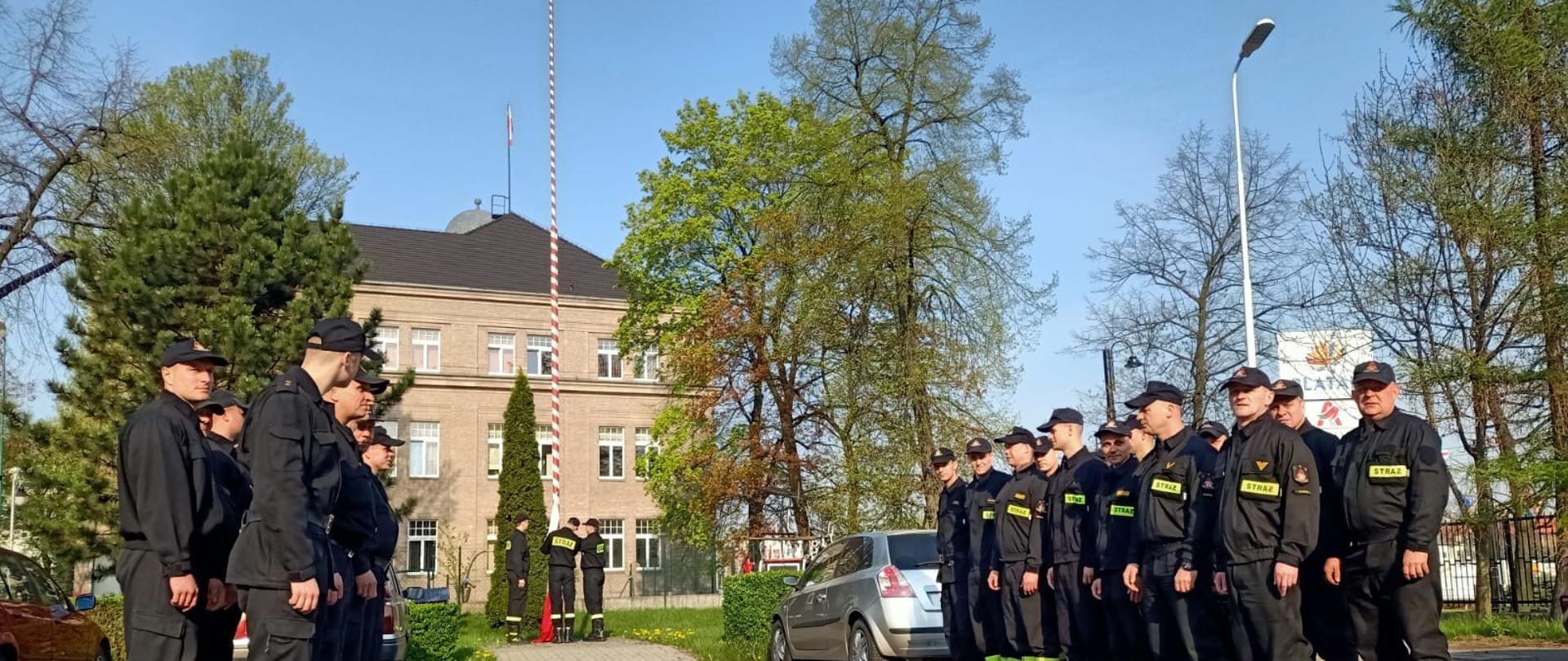 Strażacy w trakcie uroczystego podniesienia flagi państwowej na maszt.