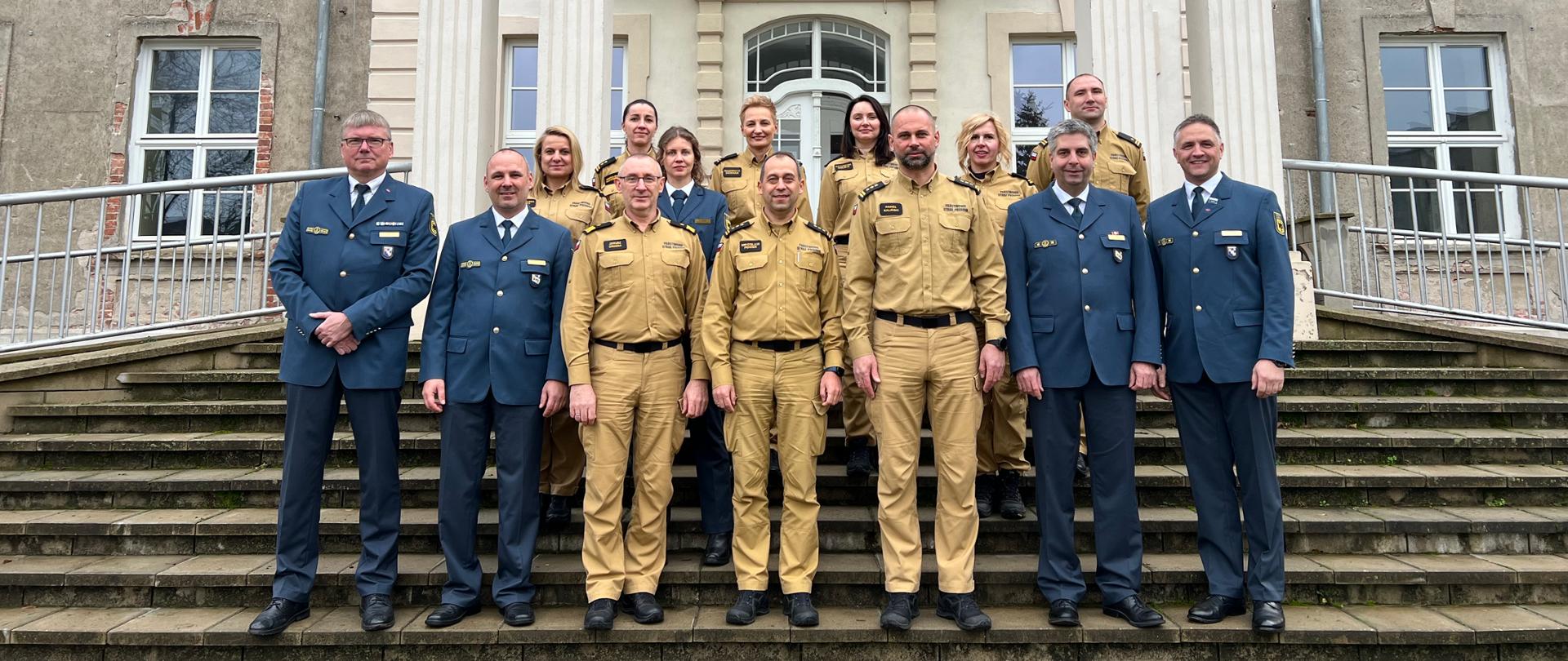 na pierwszym planie widoczni są przedstawiciele państwowej straży pożarnej oraz federalnej służby thw. wszyscy stoją na schodach przed muzeum znajdującym się w pałacu siemczyno. na drugim planie widoczne są białe połączone ze sobą kolumny znajdujące się bezpośrednio przed wejściem do budynku. na łączniku między kolumnami znajduje się brązowy napis muzeum.