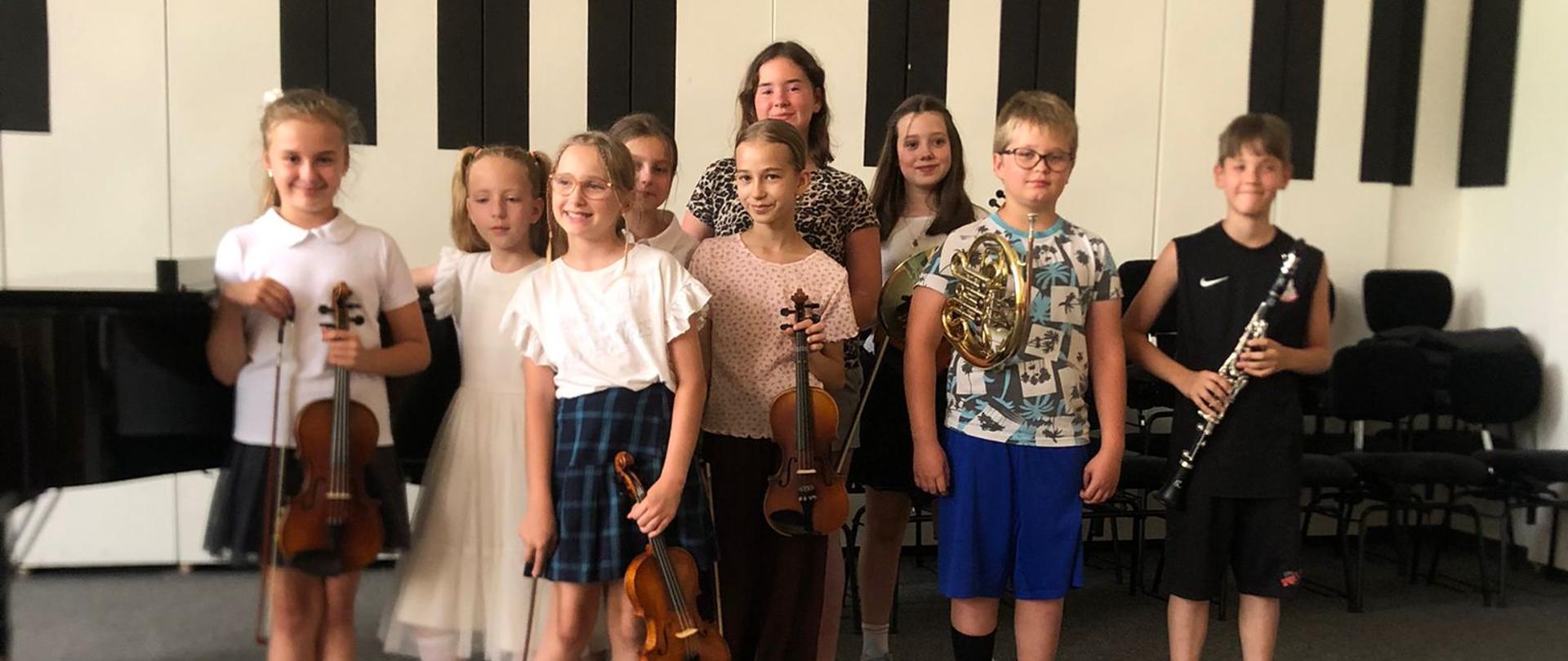 Wszyscy wykonawcy stoją z instrumentami na scenie.