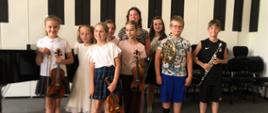 Wszyscy wykonawcy stoją z instrumentami na scenie.