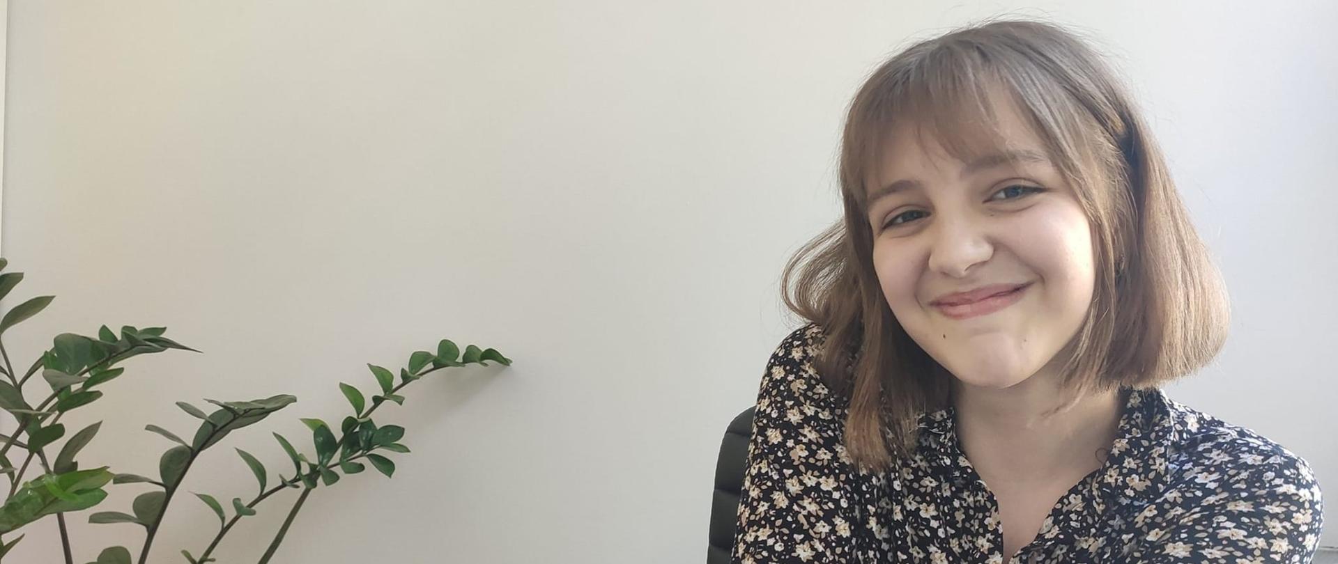 Sylwetka uśmiechniętej Natalii siedzącej przy stoliku