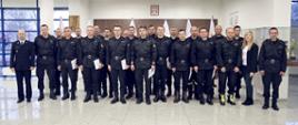 Grupowe zdjęcie uczestników szkolenia (20 funkcjonariuszy PSP) w towarzystwie Zastępcy Komendanta Centralnej Szkoły PSP oraz dwóch funkcjonariuszy CS PSP i kobiety
