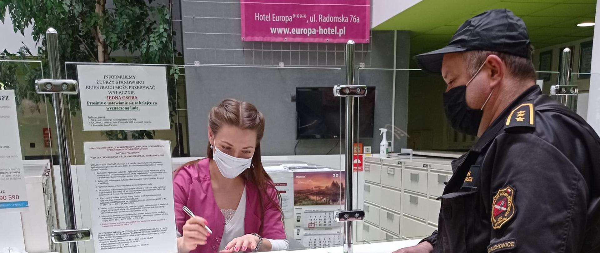 Funkcjonariusz przekazujący ŚOI pracownikowi punktu szczepień.