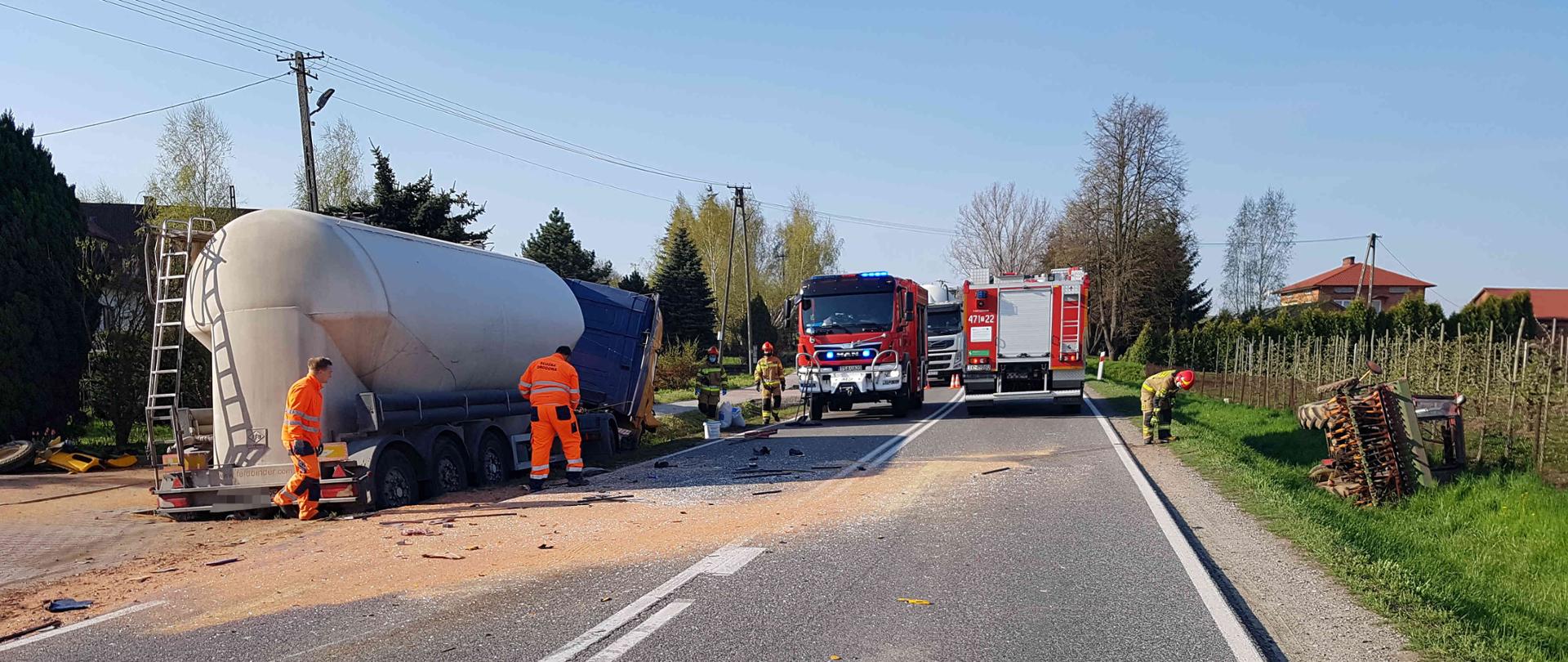 Zdjęcie przedstawia samochody pożarnicze, strażaków podczas działań, samochody uczestniczące wypadku znajdujące się przydrożnych rowach oraz strażaków usuwających rozlewiska płynów.