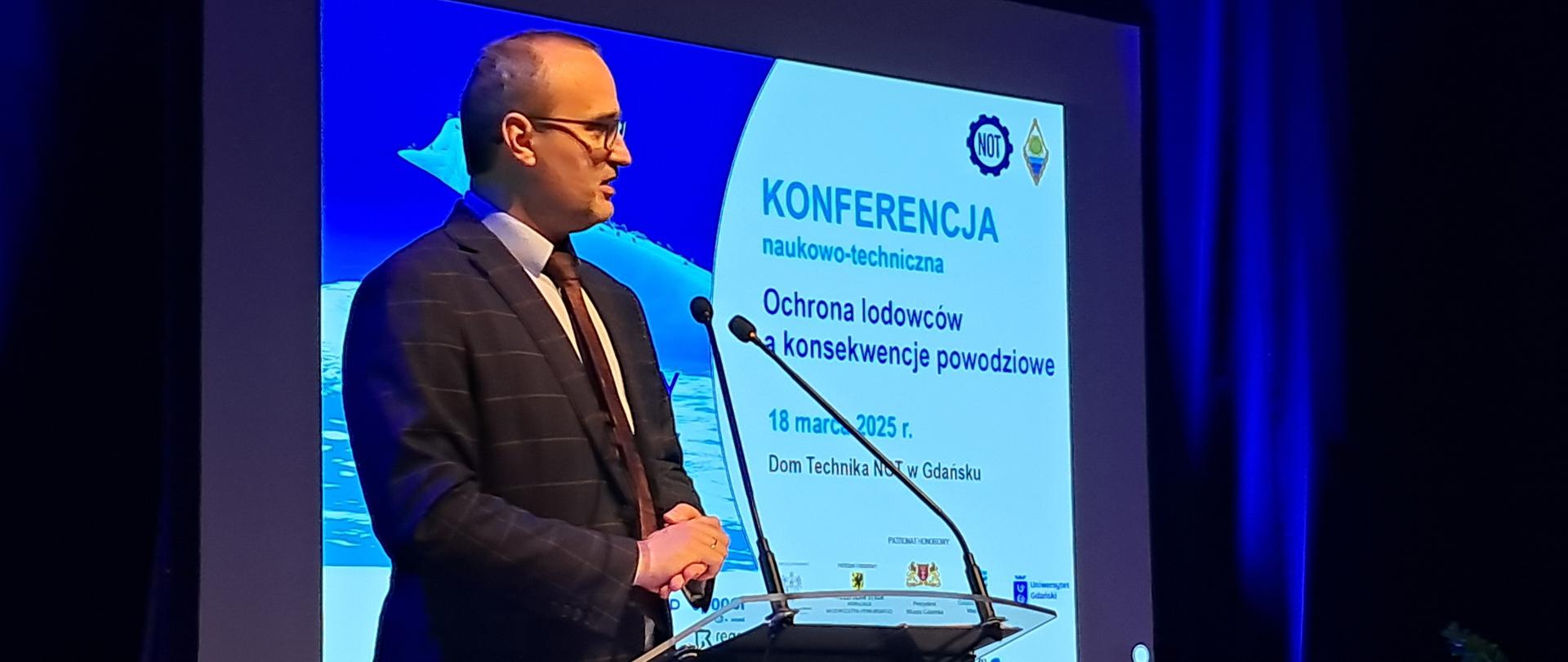 mężczyzna stoi za pulpitem i przemawia