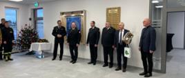 W sali szkoleniowej Komendant Miejski Państwowej Straży Pożarnej w Elblągu wita przybyłych gości. Z boku, z lewej strony widoczna przystrojona choinka.
