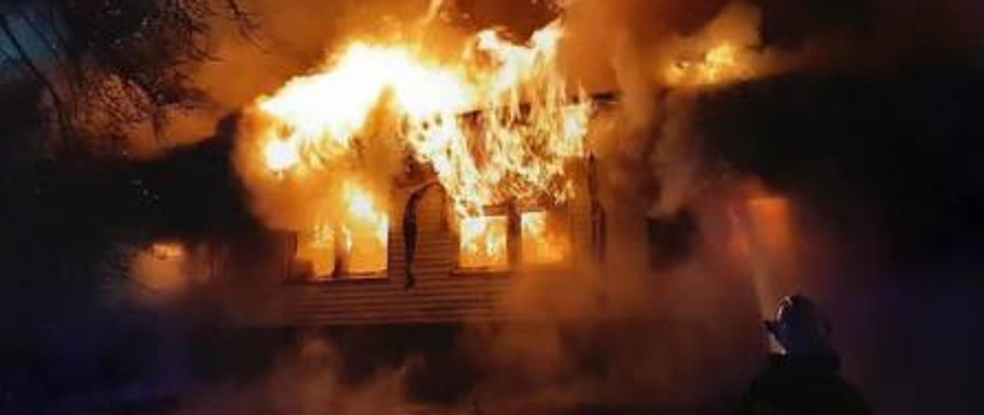 Widok strażaków gaszących stary budynek gminy