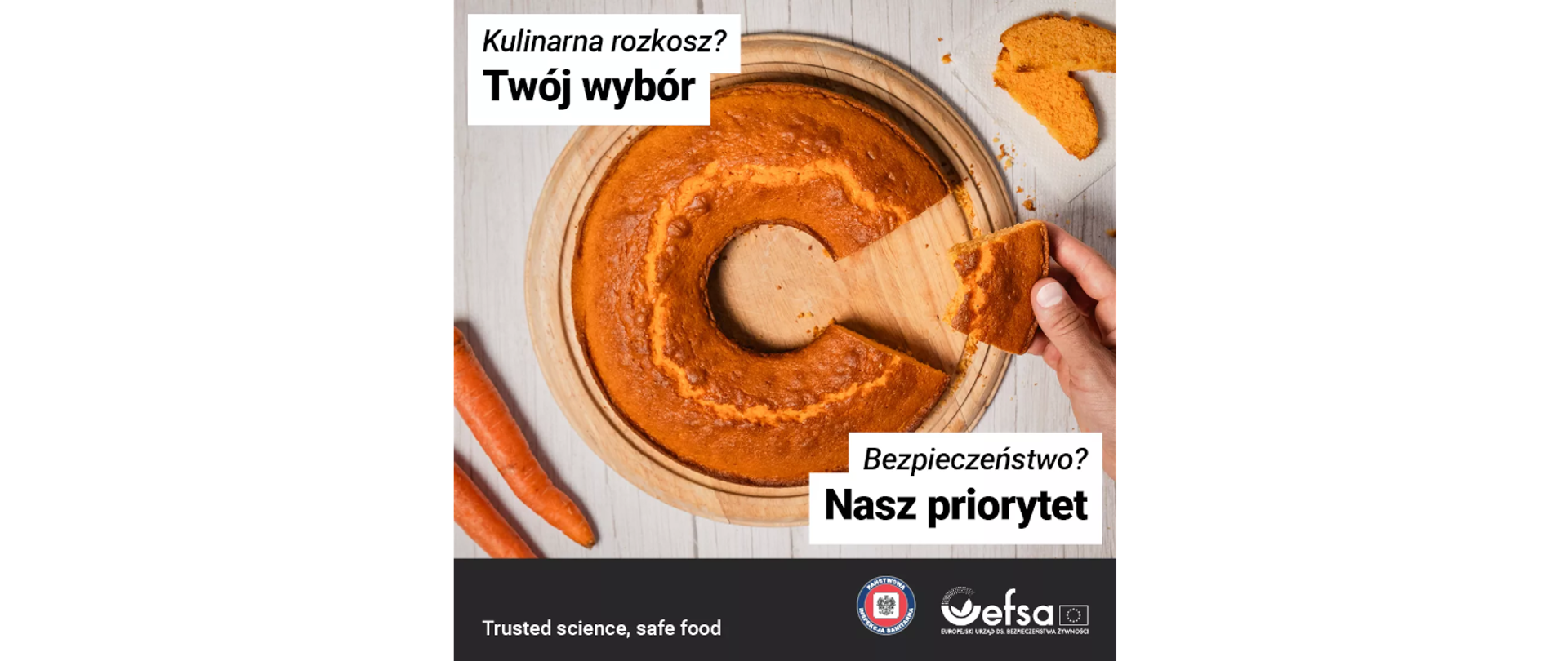 Widok z góry na okrągłe ciasto, z którego ktoś odkroił jeden kawałek. Obok ciasta leżą dwie marchewki. W lewym górnym rogu widnieje napis: „Kulinarna rozkosz? Twój wybór”, a w prawym: „Bezpieczeństwo? Nasz priorytet”. Na samym dole zdjęcia logo Państwowej Inspekcji Sanitarnej oraz EFSA oraz napis po angielsku: „Trusted science, safe food”.