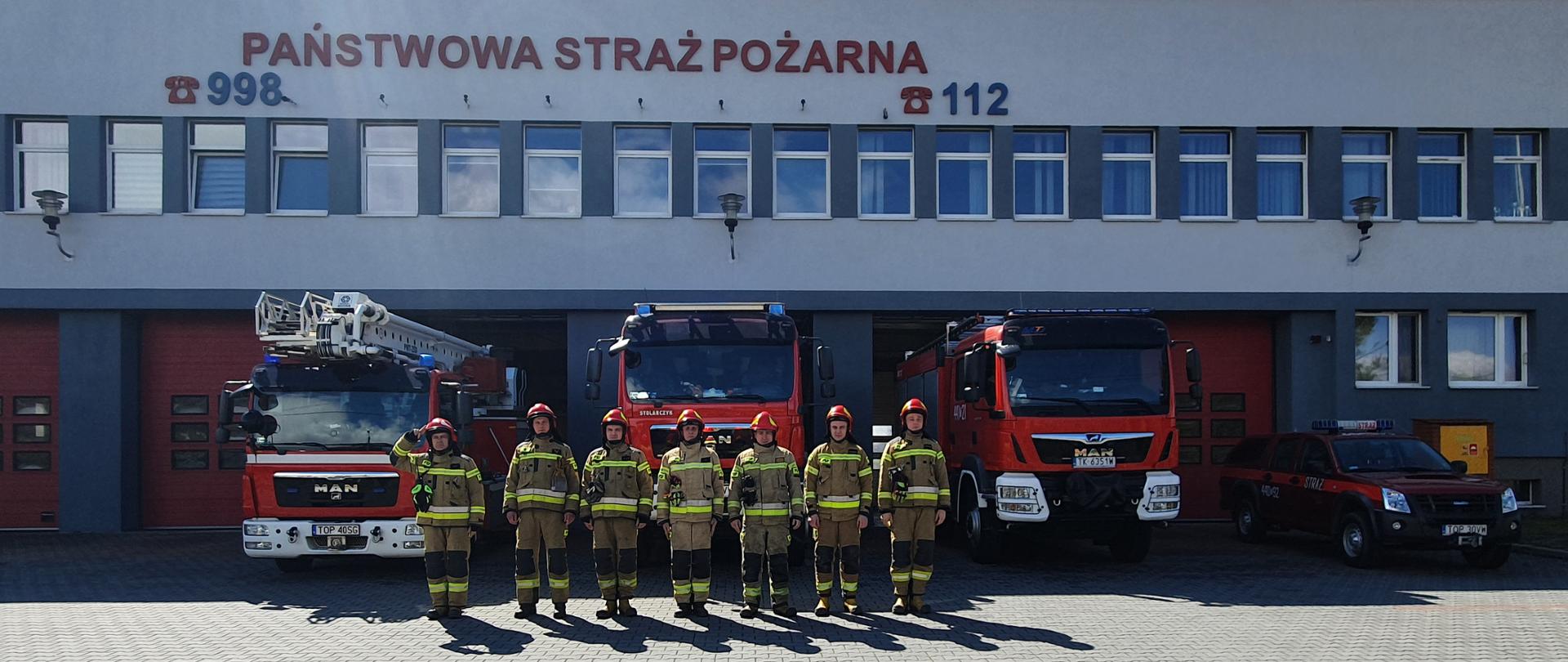 Zdjęcie przedstawia strażaków oddających honory przed KP PSP Opatów