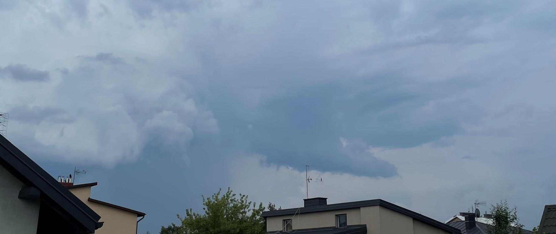 na zdjęciu chmura burzowa i fragmenty dachów kilku domów