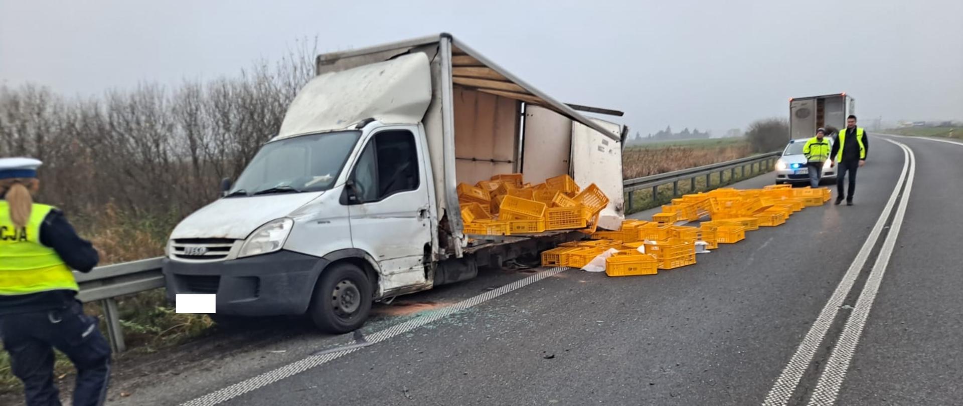 Widać uszkodzony samochód dostawczy, na drodze znajdują się skrzynki