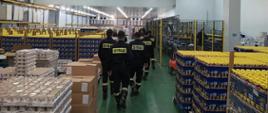 Funkcjonariusze KP PSP Kozienice na terenie hali magazynowej obiektu „Obory Sp. z o.o.” w Kozienicach, po bokach widać magazynowane produkty
