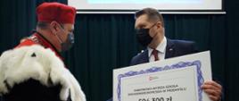 Minister Przemysław Czarnek przekazuje rektorowi jednej z podkarpackich uczelni symboliczny czek.