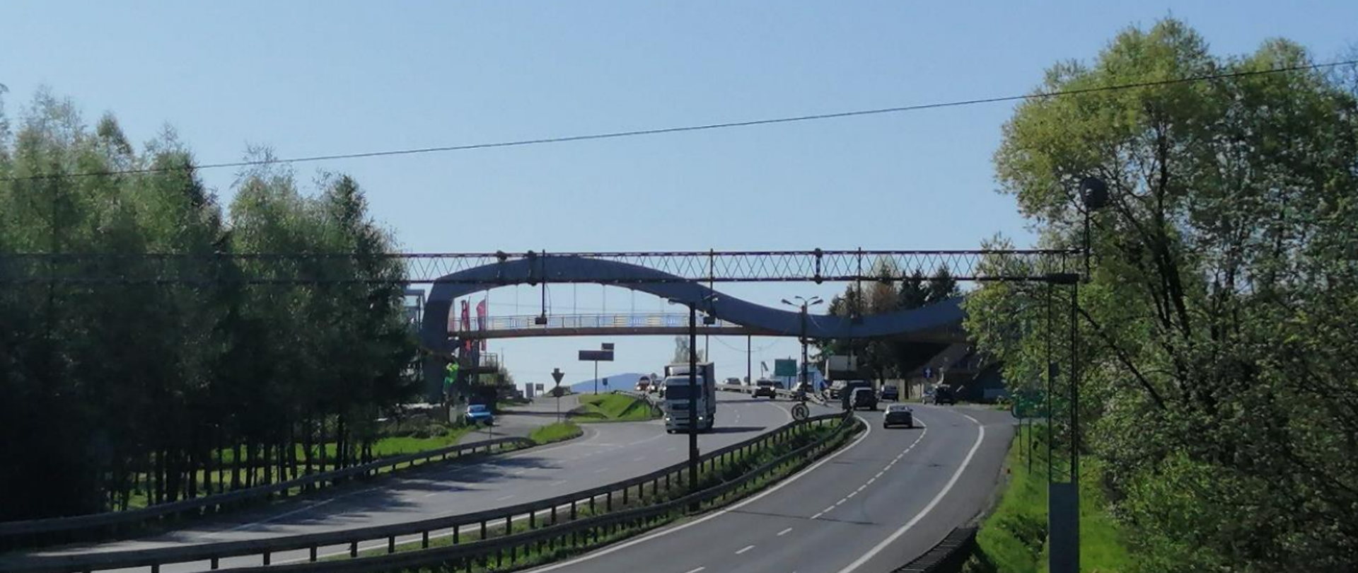 Zakopianka w Jaworniku, w tle kładka dla pieszych, wokół drogi zadrzewienia