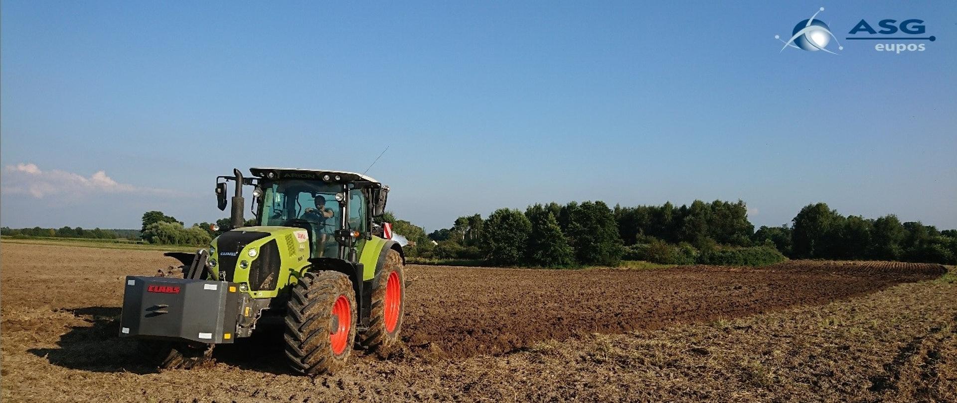 Ilustracja prezentująca ciągnik rolniczy w trakcie prac polowych
