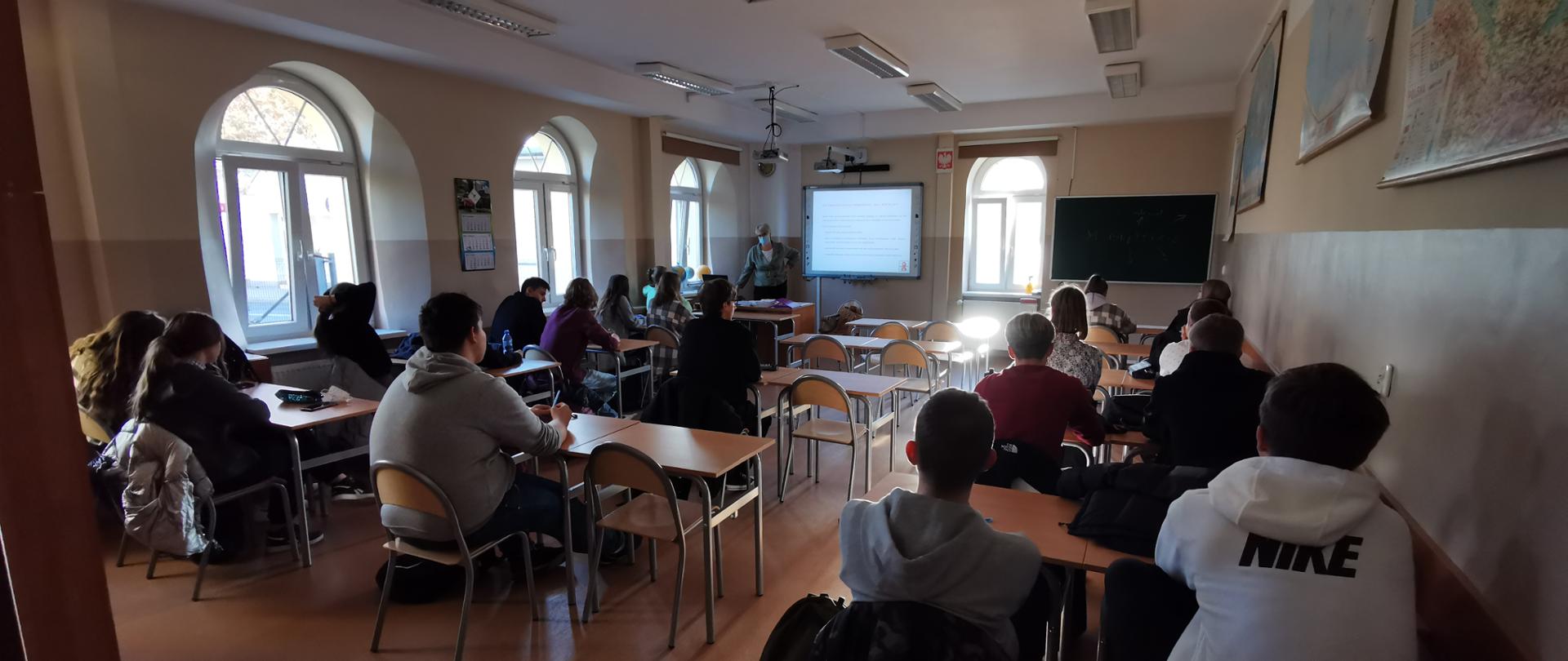 Uczniowie w szkolnej sali słuchają wykładu