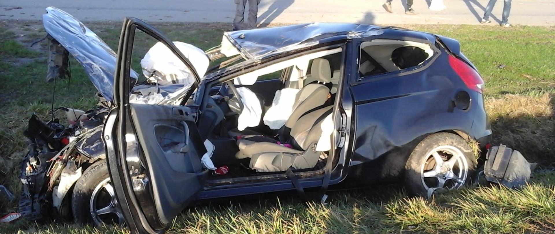 Auto osobowe stojące w przydrożnym rowie. Auto zniszczone w wyniku dachowania.