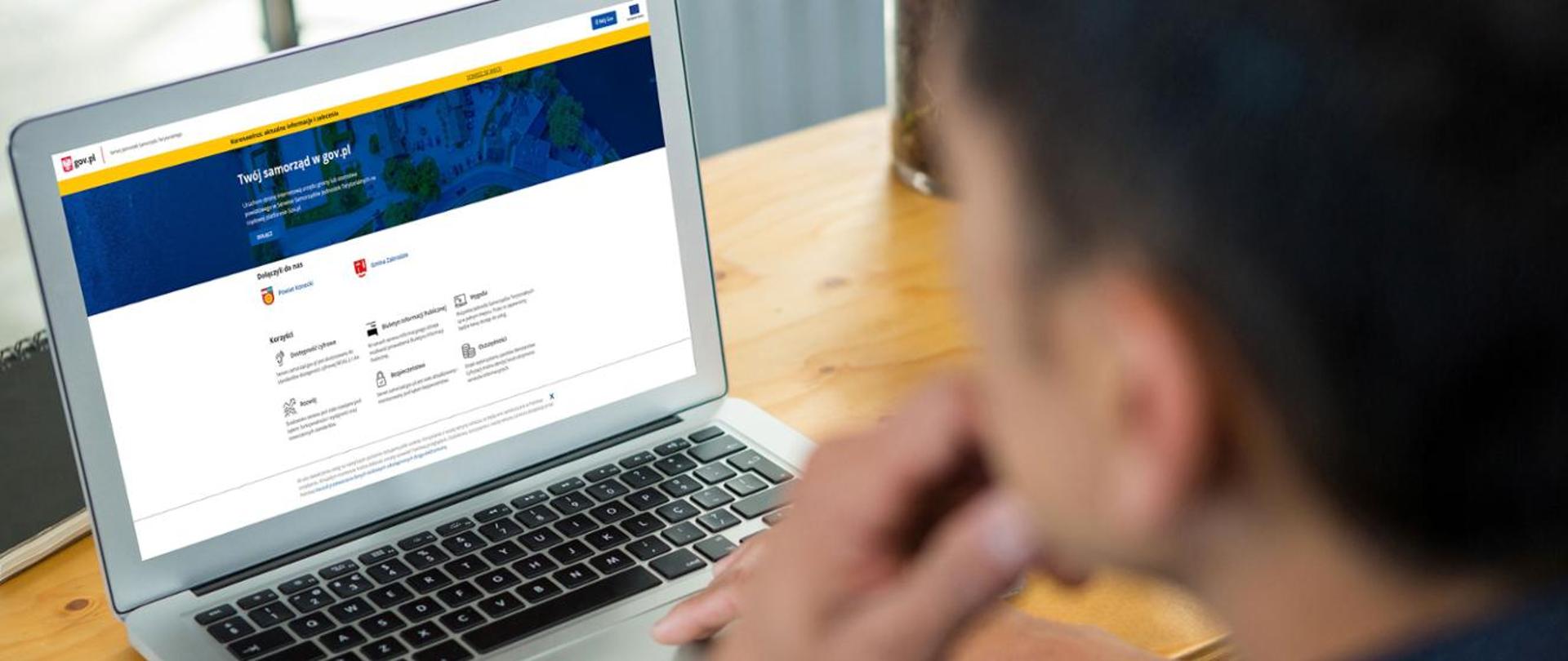 Laptop z wyświetlającą się stroną internetową, z boku profil mężczyzny