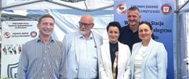Osoby pozujące do zdjęcia na tle namiotu wystawienniczego PIS na Dożynkach Wojewódzkich w gminie Oława