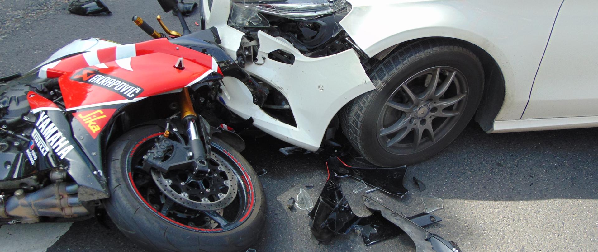 Na zdjęciu widać samochód osobowy i motocykl, które zderzyły się.