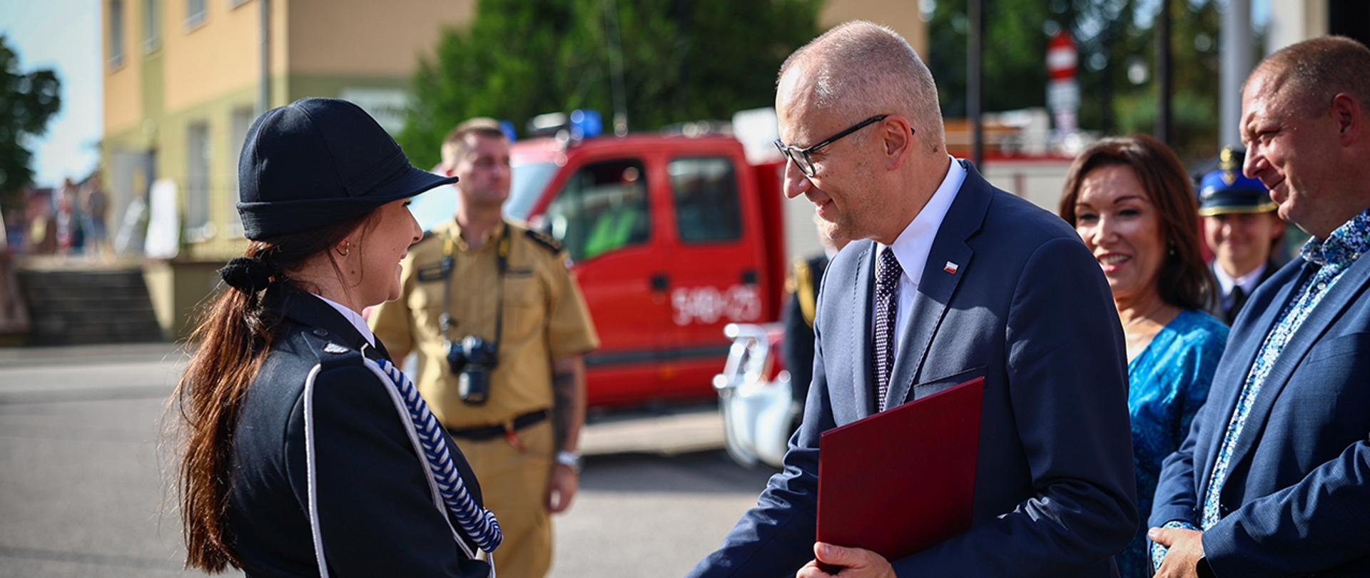 Wiceminister Błażej Poboży wręcza list gratulacyjny prezes OSP.