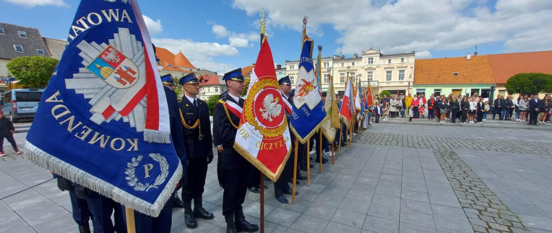 Poczty sztandarowe stoją na gostyńskim rynku. W tle znajdują się mieszkańcy.