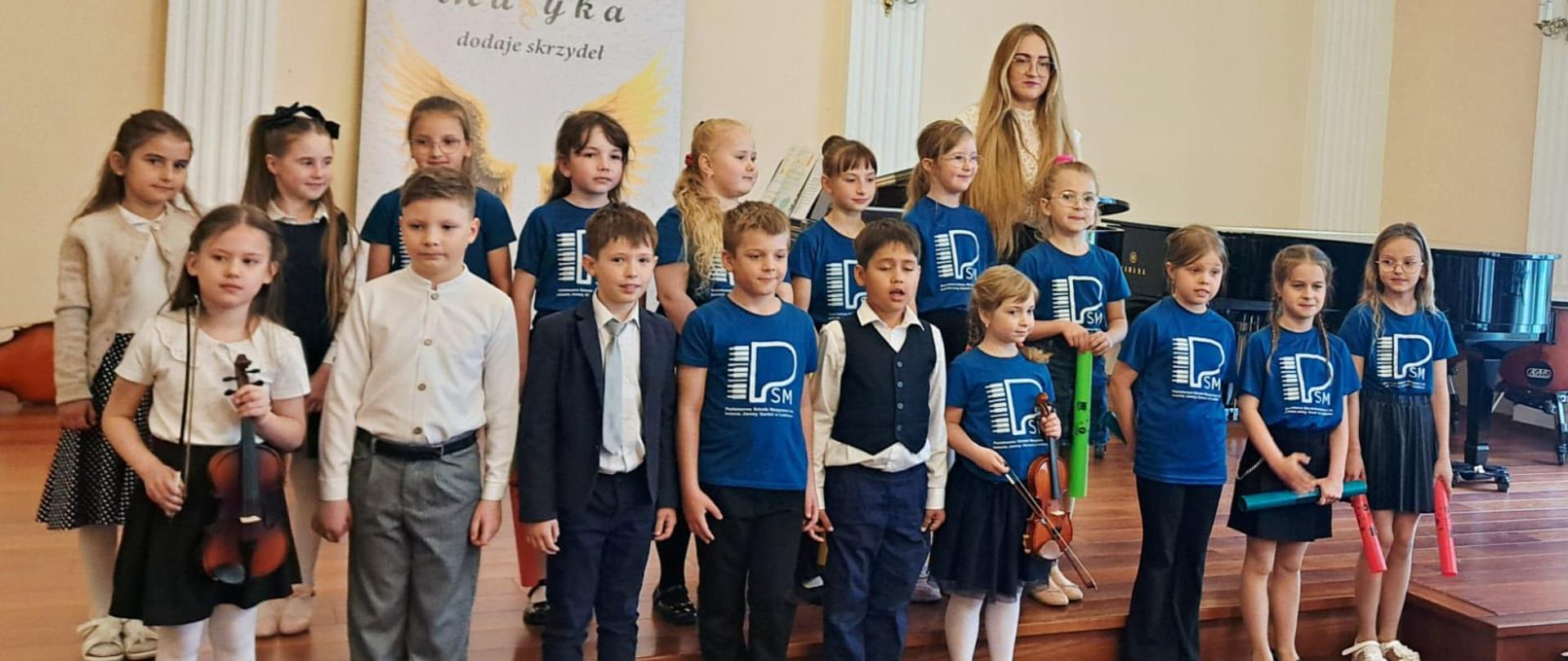 Uczniowie klasy I cyklu 6 na scenie sali koncertowej podczas popisu w Państwowej Szkole Muzycznej I st. w Lublińcu