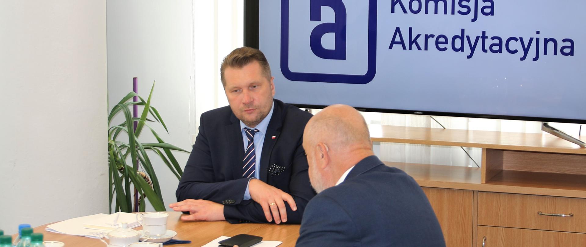 Minister Edukacji i Nauki Przemysław Czarnek siedzi przy stole z mężczyzną.
