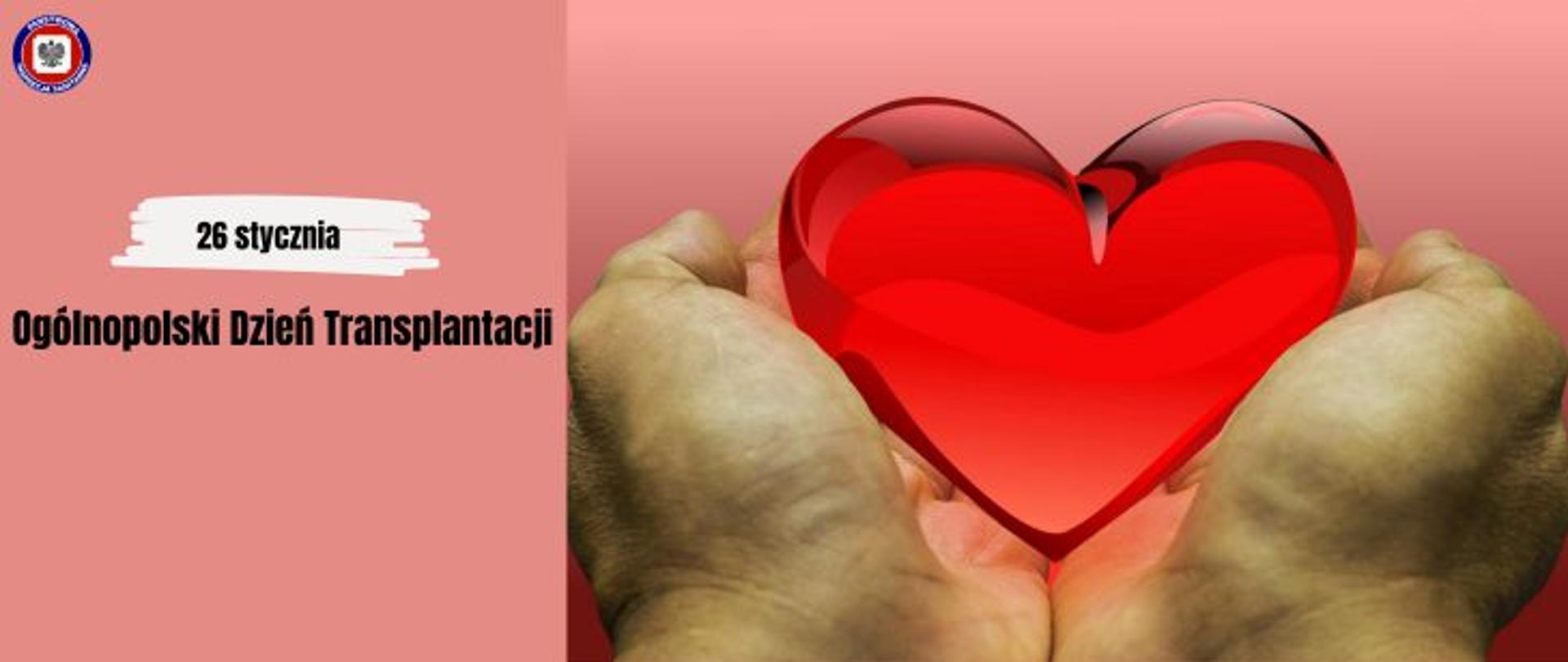 Po prawej dłonie trzymające kryształowe czerwone serce, po lewej na morelowym tle czarny napis Ogólnopolski Dzień Transplantacji 26 stycznia, w lewym górnym rogu logo Państwowej Inspekcji Sanitarnej.