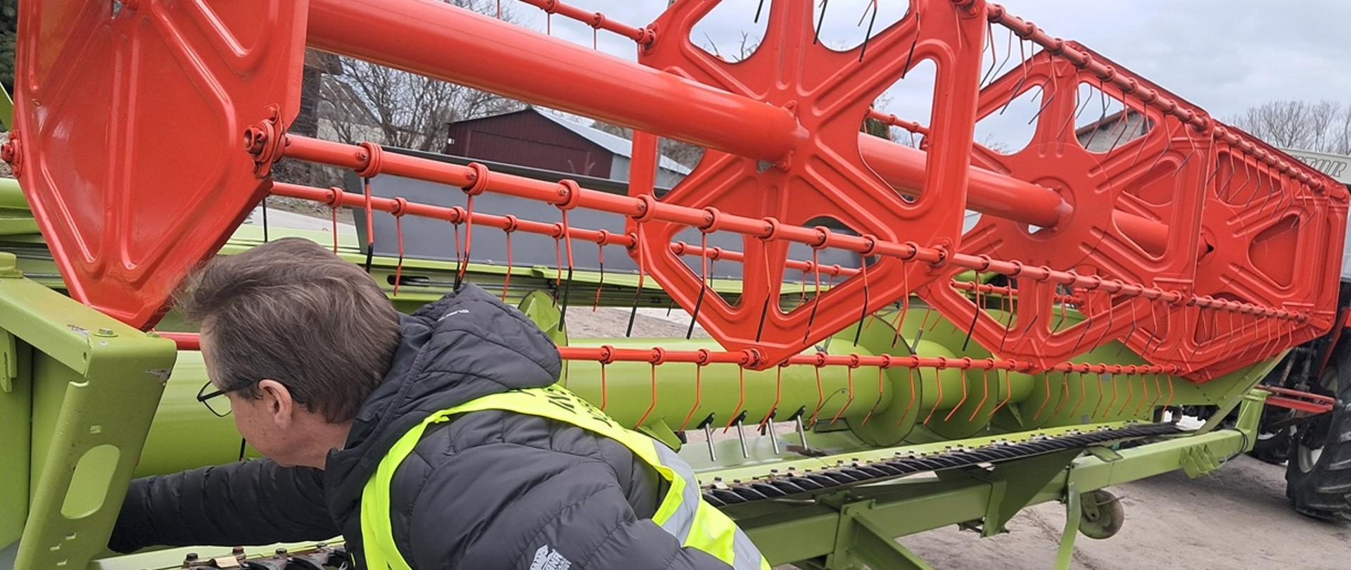 Inspektor ogląda zespól żniwny zwany hederem oraz wózek do jego transportu.