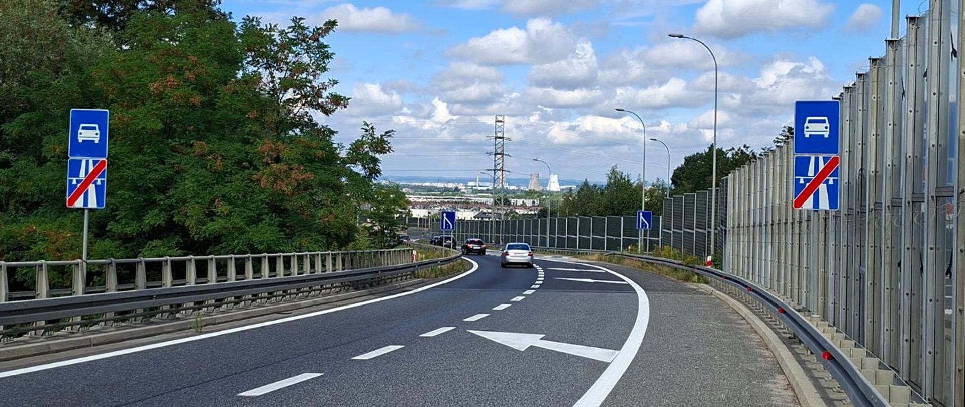 Węzeł Bieżanów, łącznica z A4 na S7, dwa pasy łącznicy, prawy pas zanikający, w oddali zabudowania Krakowa i kominy elektrociepłowni