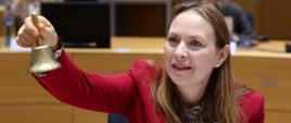 Minister funduszy i polityki regionalnej Katarzyna Pełczyńska-Nałęcz siedzi na sali posiedzeń i trzyma w prawej dłoni dzwonek