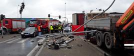 zdjęcie przedstawia Wypadek w m. Rzgów na skrzyżowaniu DK 91 i DK 71. Widoczną sygnalizację świetlną, w tle stoją samochody straży pożarnej i policji