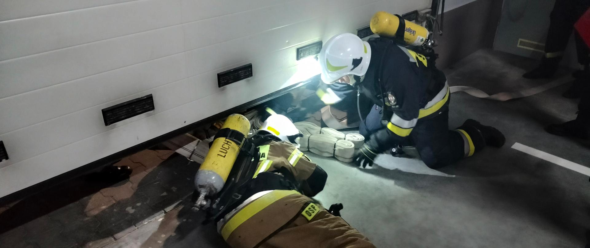 Zdjęcie przedstawia 2 strażaków podczas przechodzenia pod przeszkodą. 