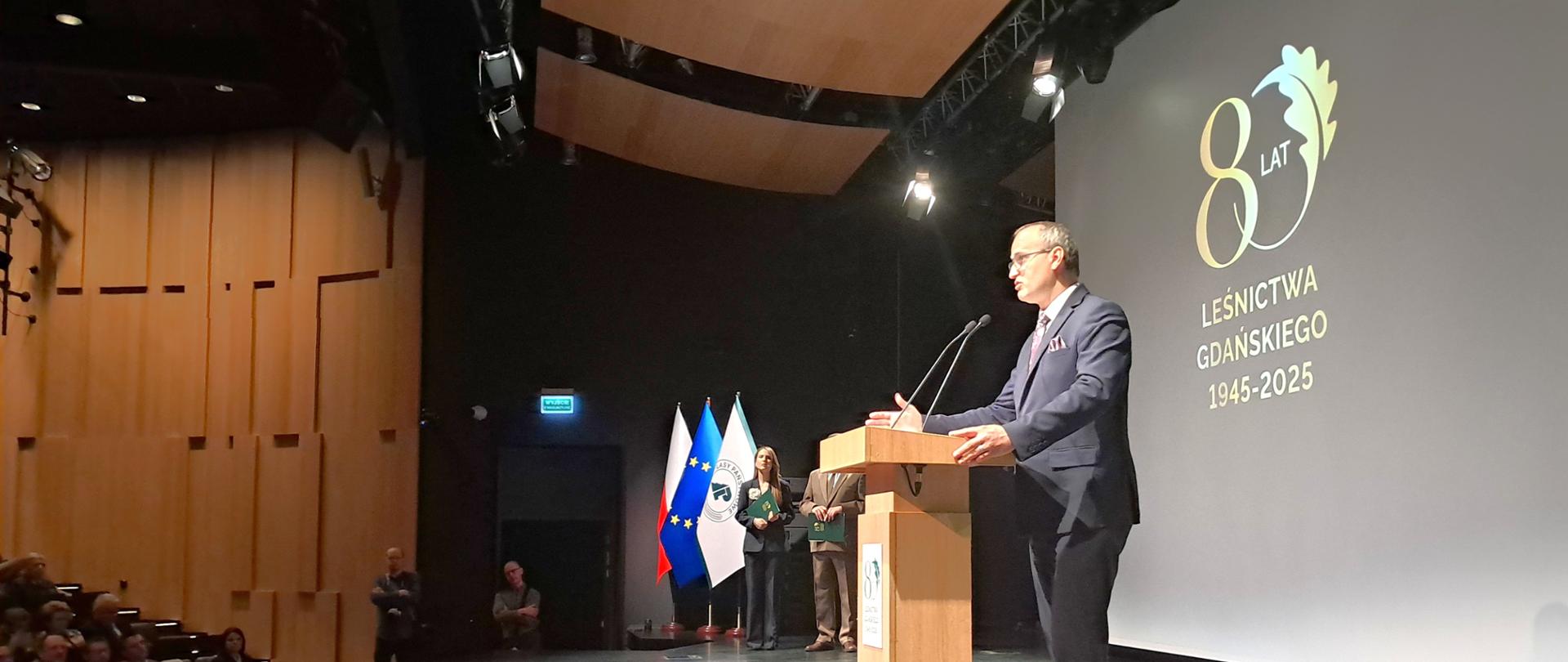 mężczyzna stoi na scenie i przemawia