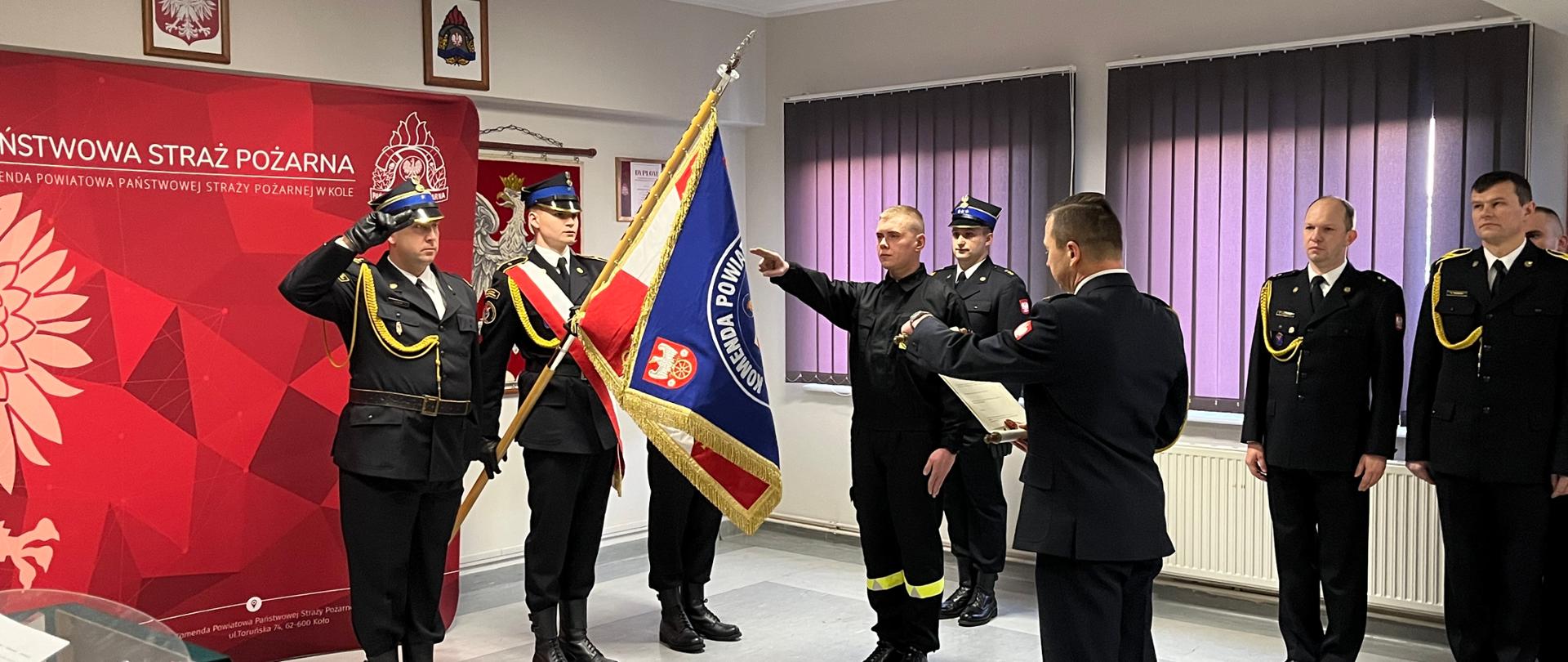 Zdjęcie przedstawia złożenie ślubowania przez nowoprzyjętego strażaka w obecności funkcjonariuszy 