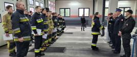 W prawej części zdjęcia Komendant, Prezes OSP i towarzyszący funkcjonariusze wręczają zaświadczenie kursantce. W prawej części zdjęcia strażacy kursanci stoją w dwuszeregu.