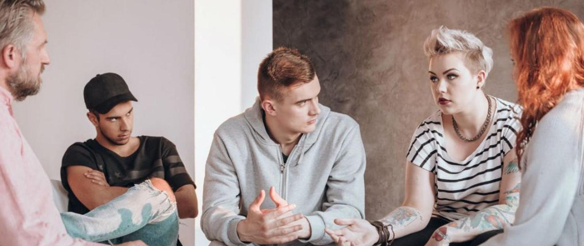 na zdjęciu trzech mężczyzn i dwie kobiety dyskutują na jakiś temat