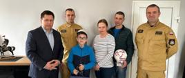 MŁODY BOHATER. 12-letni Patryk wraz z rodzicami podczas wizyty w KP PSP w Kościanie, Komendant wraz z Zastępcą i wicewójtem gminy Kościan wręczają listy gratulacyjne i podziękowania.
