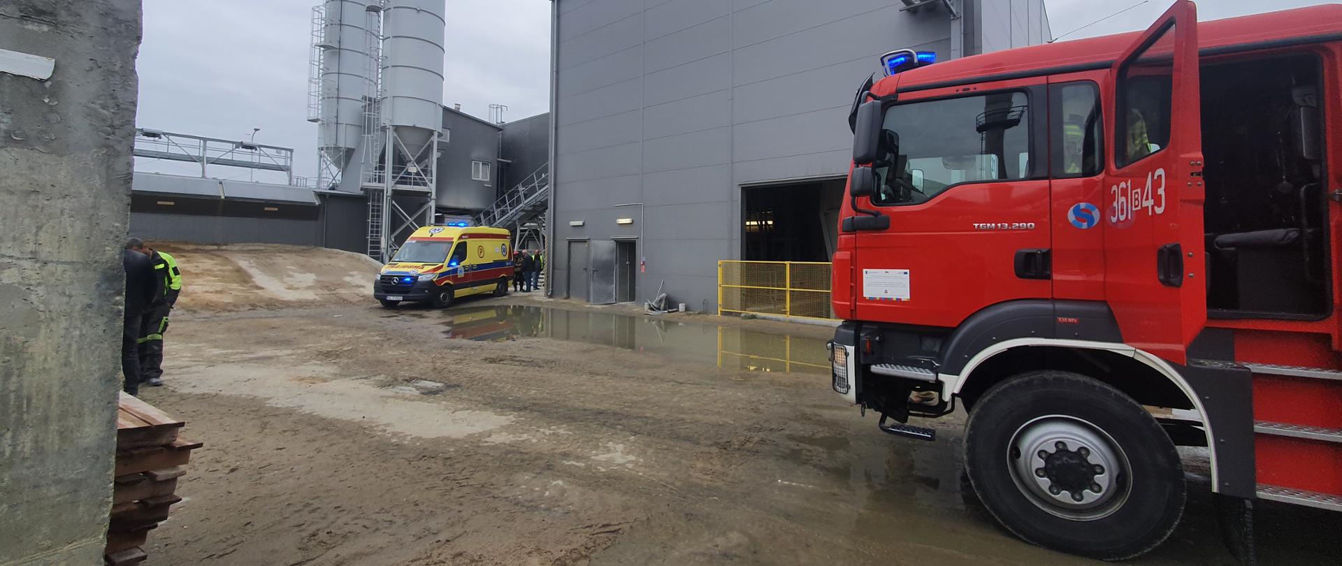 Samochód pożarniczy wraz z karetką pogotowia przed budynkiem na placu zakładu produkcyjnego
