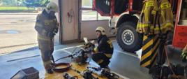 Strażacy obsługujący urządzenie hydrauliczne wewnątrz garażu