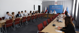 Na zdjęciu widać młodych ludzi siedzących wzdłuż stołów. Na końcu siedzi wiceminister Tadeusz Kościński. Za nim plansza z logo MPiT.