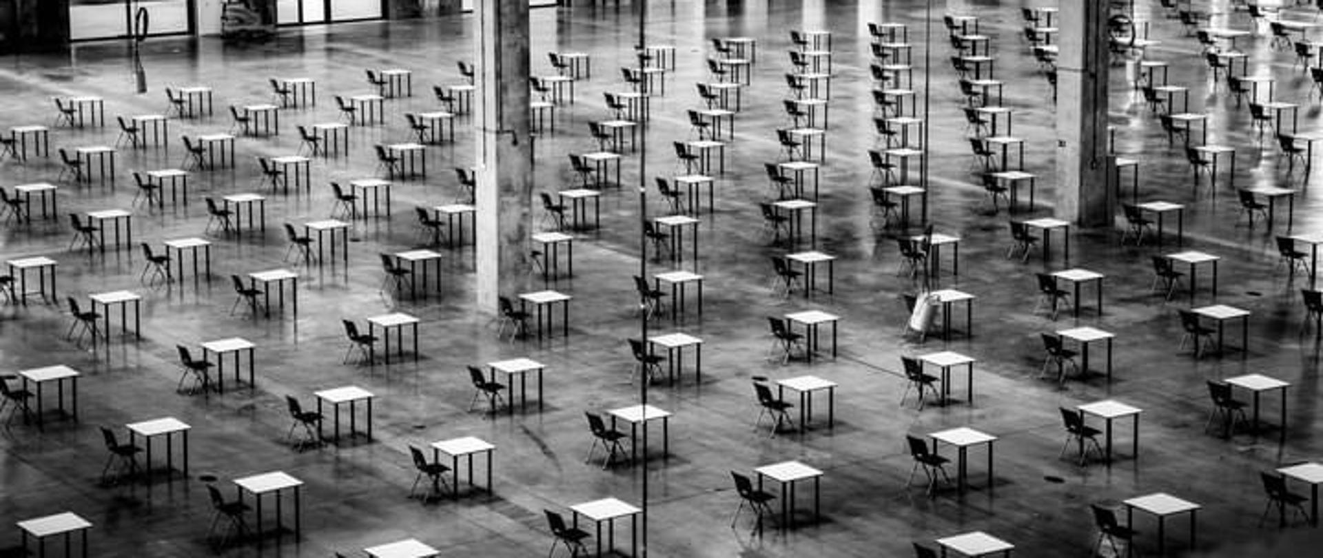 jednoosobowe stoliki w dużych odstępach od siebie i w dużym pomieszczeniu. 