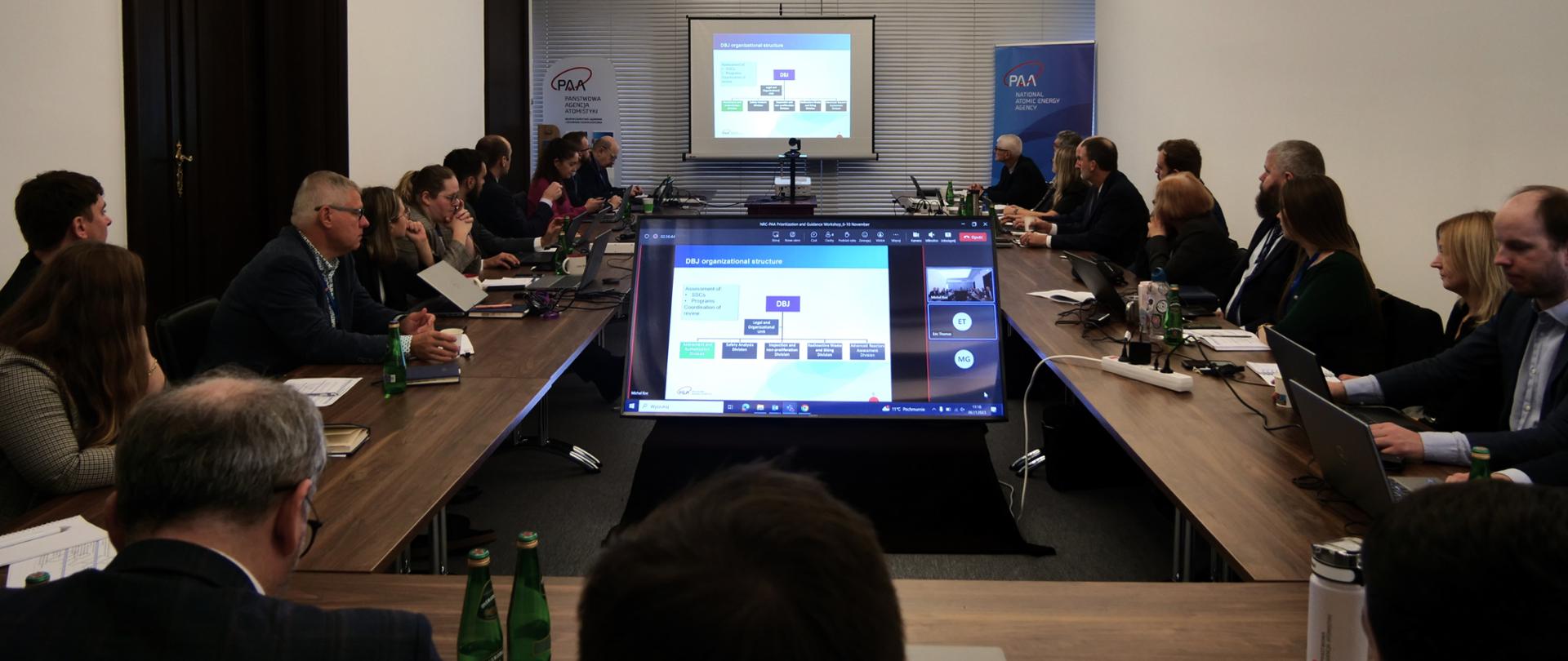 Warsztat z udziałem ekspertów amerykańskiej Komisji Bezpieczeństwa Jądrowego - uczestnicy siedzą wokół stołu i słuchają wystąpienia prelegenta