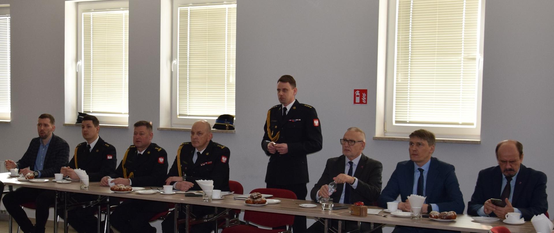 Przemówienie Komendanta Powiatowego PSP w Wąbrzeźnie podczas narady rocznej. Po prawej oraz lewej stronie zaproszeni goście oraz pracownicy KP. 