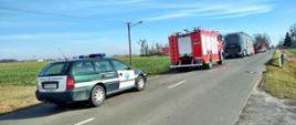 Inspekcja Transportu Drogowego na miejscu zdarzenia. Na pierwszym planie radiowóz ITD, następnie pojazdy straży pożarnej i ciężarówka na lokalnej drodze.