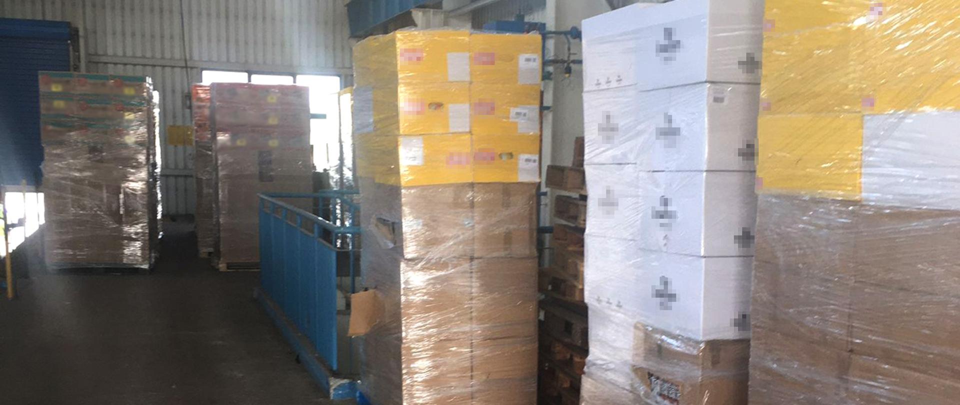 Palety z kartonami z nielegalnymi papierosami w magazynie.