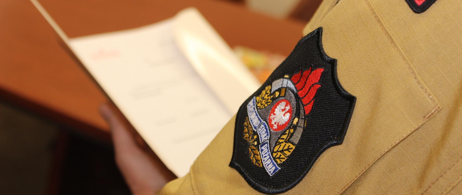 Zdjęcie poglądowe. Naszywka z logo PSP na rękawie munduru służbowego.