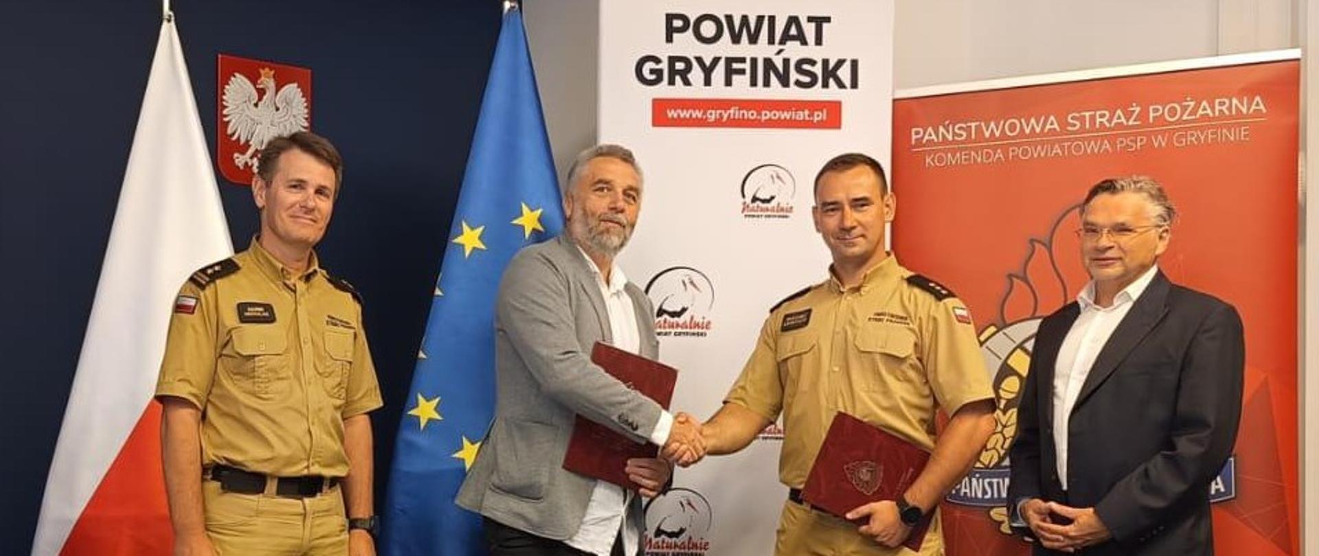 Uściśnięcie dłoni. Od lewej: brygadier Marek Michalak - Zastępca Zachodniopomorskiego Komendanta Wojewódzkiego PSP, Daniel Niedbała - właściciel biura projektowego A. DO XXI Sp. z o.o., kapitan Maciej Łempicki - Komendant Powiatowy PSP w Gryfinie, Wojciech Konarski - Wicestarosta gryfiński.